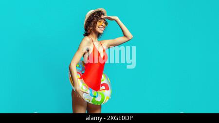 Frau in rotem Badeanzug mit Floatie, die in Richtung Horizont blickt Stockfoto