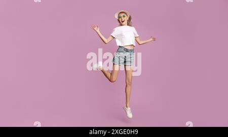 Happy Young Woman springt in weißem Oberteil und Denim-Shorts Stockfoto