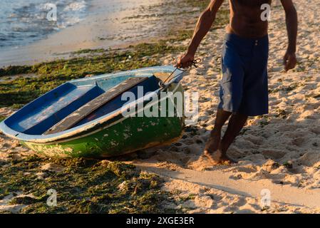 Salvador, Bahia, Brasilien - 27. Januar 2019: Fischer ziehen ein Boot auf den Strand von Rio Vermelho in der Stadt Salvador, Bahia. Stockfoto