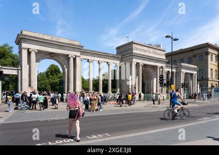 Eine Frau überquert die Straße vor den berühmten drei Bögen und Säulen des Hyde Park Screen von Decimus Burton und wurde 1828 in London, Großbritannien fertiggestellt Stockfoto