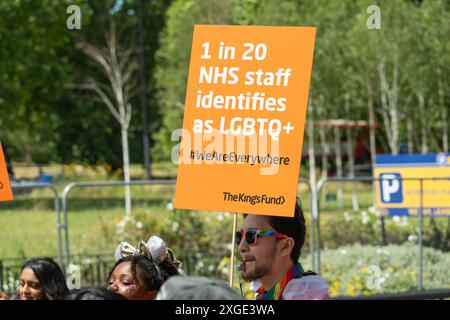 Person, die ein Plakat hält, auf dem jeder 20 NHS-Mitarbeiter bei der London 2024 Pride Parade, Park Lane, Samstag, den 29. Juni, England, als LGBTQ+ identifiziert wird Stockfoto