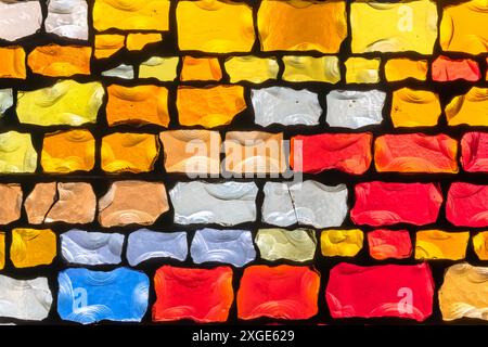 Nahaufnahme eines Kirchenmosaiks mit lebendigen Glasfliesen in verschiedenen Farben, darunter Rot, Gelb, Orange und mehr, wobei jede Fliese eine einzigartige Textur hat Stockfoto