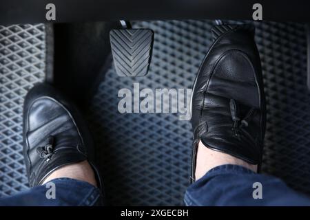 Mann in schwarzen Schuhen, der auf das Pedal der Autobremse drückt, Nahaufnahme Stockfoto