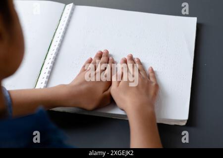 Hände eines birassischen Schulmädchens, das brailleschrift im Schulunterricht liest, mit Kopierraum Stockfoto