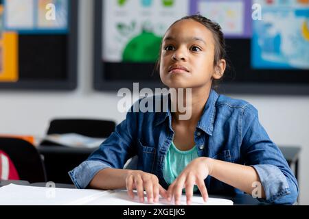 Blindes birassisches Schulmädchen sitzt am Schreibtisch in klassenschrift, mit Kopierraum Stockfoto