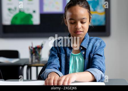 Blindes birassisches Schulmädchen sitzt am Schreibtisch in klassenschrift, mit Kopierraum Stockfoto