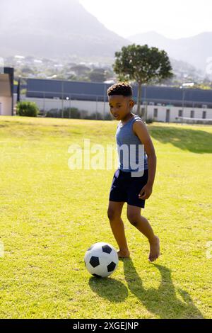 Glücklicher afroamerikanischer Schuljunge, der in der Schule Fußball spielt Stockfoto