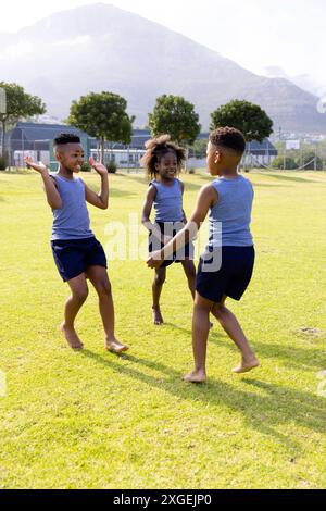 Glückliche afroamerikanische Schulkinder spielen Fußball auf dem Schulfeld Stockfoto