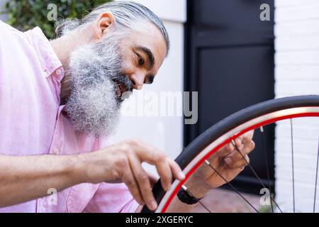 Repariert Fahrradreifen, Mann fokussiert auf die Befestigung des Rads draußen Stockfoto