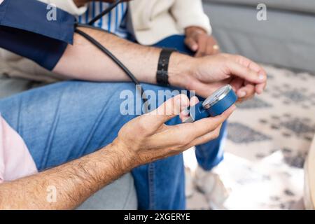 Blutdruckkontrolle, Mann mit Sphygmomanometer und Seniorenpaar sitzen Stockfoto