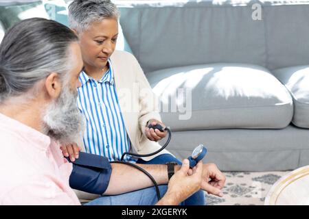Blutdruck überprüfen, Seniorin hilft Mann mit Monitor auf Couch, Kopierraum Stockfoto