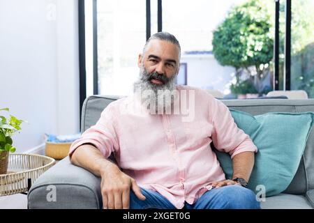 Entspannen Sie auf dem Sofa, ein älterer Mann mit Bart bei Videogesprächen im Wohnzimmer Stockfoto
