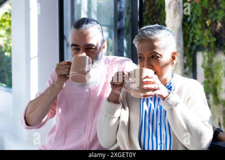 Seniorenpaar trinkt zusammen Kaffee und genießt die Morgenzeit am Fenster Stockfoto