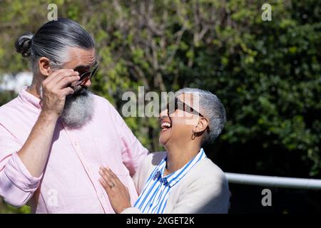 Seniorenpaar lacht und genießt die gemeinsame Zeit im Freien, trägt eine Sonnenbrille Stockfoto