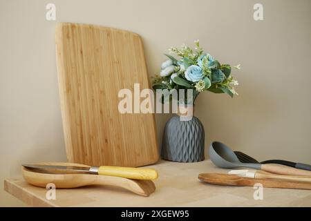 Schneidebrett aus Holz mit Kochutensilien und Blumenvase auf der Küchenzeile Stockfoto