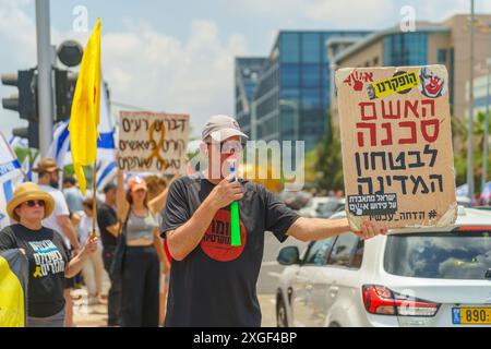 Haifa, Israel - 07. Juli 2024: Menschen protestieren mit Fahnen, verschiedenen Schildern, die eine große Kreuzung blockieren. Teil des Tages der Störung gegen die Regierung A Stockfoto