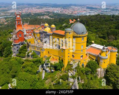 Beeindruckendes Schloss mit bunten Türmen und Kuppeldach auf einem Bergrücken inmitten grüner Bäume und breiter Landschaft, Blick aus der Vogelperspektive, Palacio Nacional da Stockfoto