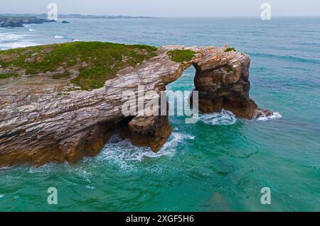 Felsiger Bogen an der Küste über dem tosenden Meer mit grün-blauem Wasser, aus der Luft, Praia das Catedrais, Playa de las Catedrales, Strand der Stockfoto