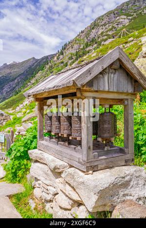Traditionelle hölzerne Gebetsmühle stehen auf einem Steinfundament inmitten einer beeindruckenden Berglandschaft, Little Tibet, Zillertal, Österreich Stockfoto