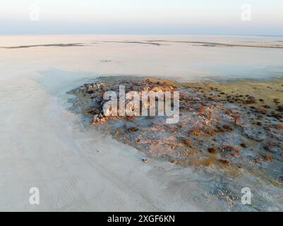 Felsige Insel mit Baobab-Bäumen in einer trockenen Salzpfanne, bei Sonnenuntergang, Geländefahrzeug auf der Salzpfanne, Blick aus der Vogelperspektive, Kubu Island, Botswana Stockfoto