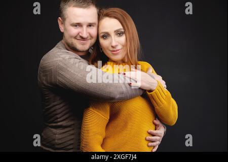 Porträt von attraktiven kaukasischen Ehepaar Mann und Frau Umarmung über schwarzem Hintergrund. Glückliche Familienbeziehungen Stockfoto