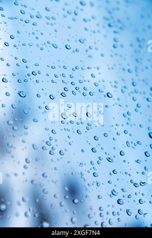 Vertikale Aufnahme. Geringe Tiefe des Feldes Wassertröpfchen auf Glas bei regnerischem Wetter, kleine Schlafbereiche im Hintergrund sind unscharf. Herbst Stockfoto