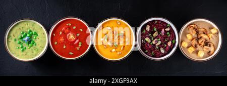 Veganes Suppenpanorama. Eine Auswahl an Gemüsesuppen, oben flach lag auf einem schwarzen Hintergrund geschossen Stockfoto