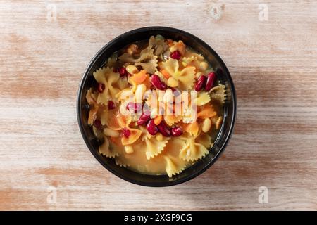 Vegane Suppe mit Pasta und Bohnen, Overhead-Schuss auf rustikalem Holzhintergrund Stockfoto