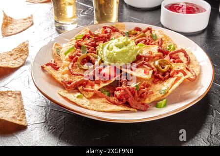 Nachos mit Rindfleisch und Tequila in einer Bar, auf einem schwarzen Tisch Stockfoto