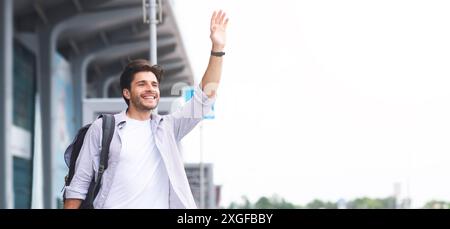Junger Mann winkende Hand in der Nähe von Flughafen Gebäude, Panorama Stockfoto