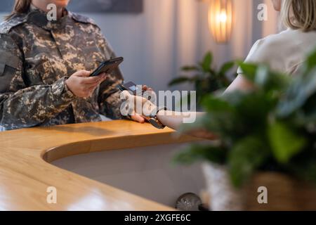 Bezahlung per Smartphone, undefiniertes Personal an der Rezeption in der medizinischen Klinik Stockfoto