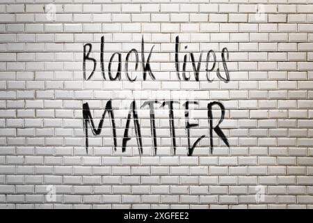 Nahaufnahme eines Phrase „Black Lives Matter“, gemalt auf einer weißen Fayence-Wand einer U-Bahn-Station. Sprühen Sie Farbe, die von einem Mitwirkenden mit dem Pinsel erstellt wurde Stockfoto