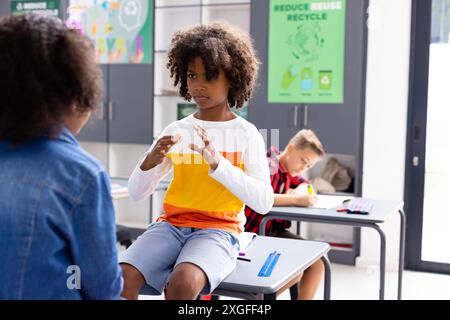 Glückliche, vielfältige Schulkinder, die Gebärdensprache im Schulunterricht benutzen Stockfoto