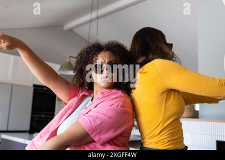 Tanzen und Spaß haben, zwei Freundinnen tragen Sonnenbrillen in der modernen Küche Stockfoto