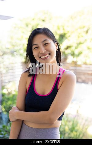 Draußen stehend, lächelnde Frau in Sportbekleidung, die den sonnigen Tag genießt Stockfoto