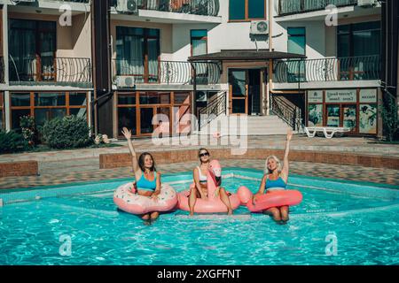 Drei Frauen sitzen auf aufblasbaren Wagen in einem Pool. Die Szene ist unbeschwert und lustig. Stockfoto