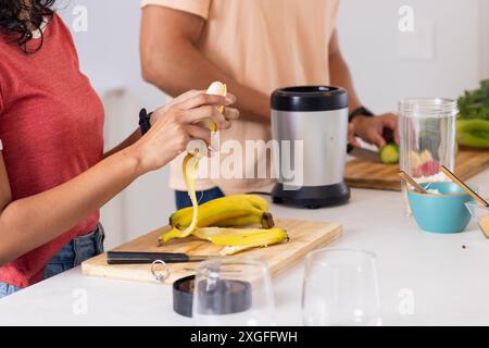 Bananenschälen, junges Paar bereitet Smoothie in der Küche mit Mixer vor Stockfoto