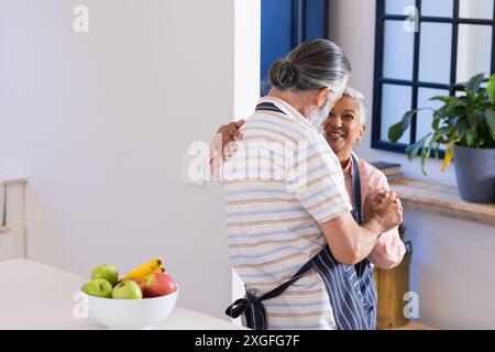 Seniorenpaar tanzt zusammen in der Küche, lächelt und genießt Momente, Kopierraum Stockfoto