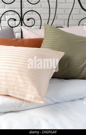 Gestreifte Kissen auf einem Bett mit Kopfteil aus schwarzem Metall Stockfoto