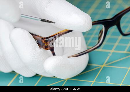 Augenoptiker Hände reparieren Brillen mit einem Werkzeug. Nahaufnahme Stockfoto