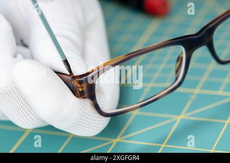 Augenoptiker Hände reparieren Brillen mit einem Werkzeug. Nahaufnahme Stockfoto