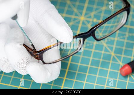 Augenoptiker Hände reparieren Brillen mit einem Werkzeug. Nahaufnahme Stockfoto