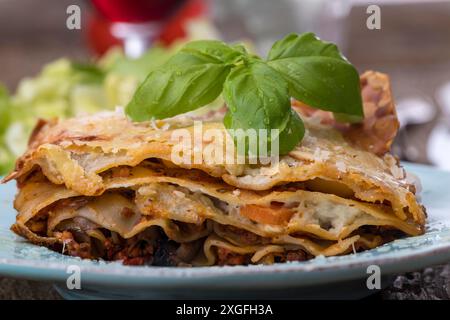 Lasagne mit Salat auf dunklem Holz Stockfoto