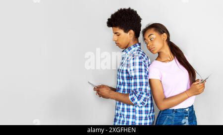 Teenager-Paar Benutzt Smartphones, Während Er Sich Hinter Den Rücken Stellt Stockfoto