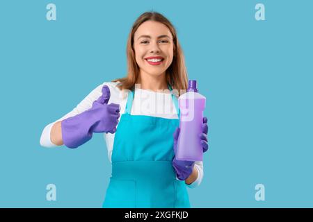 Junge Frau mit einer Flasche Waschmittel mit Daumen nach oben auf blauem Hintergrund Stockfoto