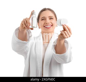 Junge Frau im Bademantel mit mizellarem Wasser und Wattepads auf weißem Hintergrund Stockfoto