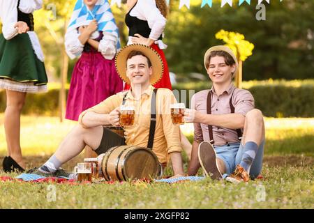 Junge Männer in traditioneller deutscher Kleidung mit Bier im Freien. Oktoberfest Stockfoto