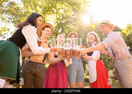 Junge Menschen in traditioneller deutscher Kleidung mit Bier und Würstchen feiern das Oktoberfest im Freien Stockfoto