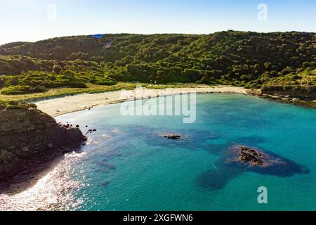 Aus der Vogelperspektive auf den Strand es Grau auf Menorca an einem sonnigen Sommertag. Unberührter Strand mit blauem, sauberem Wasser, Drohnenlandschaft der baleareninsel Menorc Stockfoto