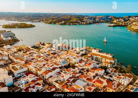 Blick aus der Vogelperspektive auf die traditionelle Stadt es Castell an der Küste Menorcas mit Hafen und Booten bei Sonnenuntergang während der Sommersaison. Malerische balearen Schlepptau Stockfoto